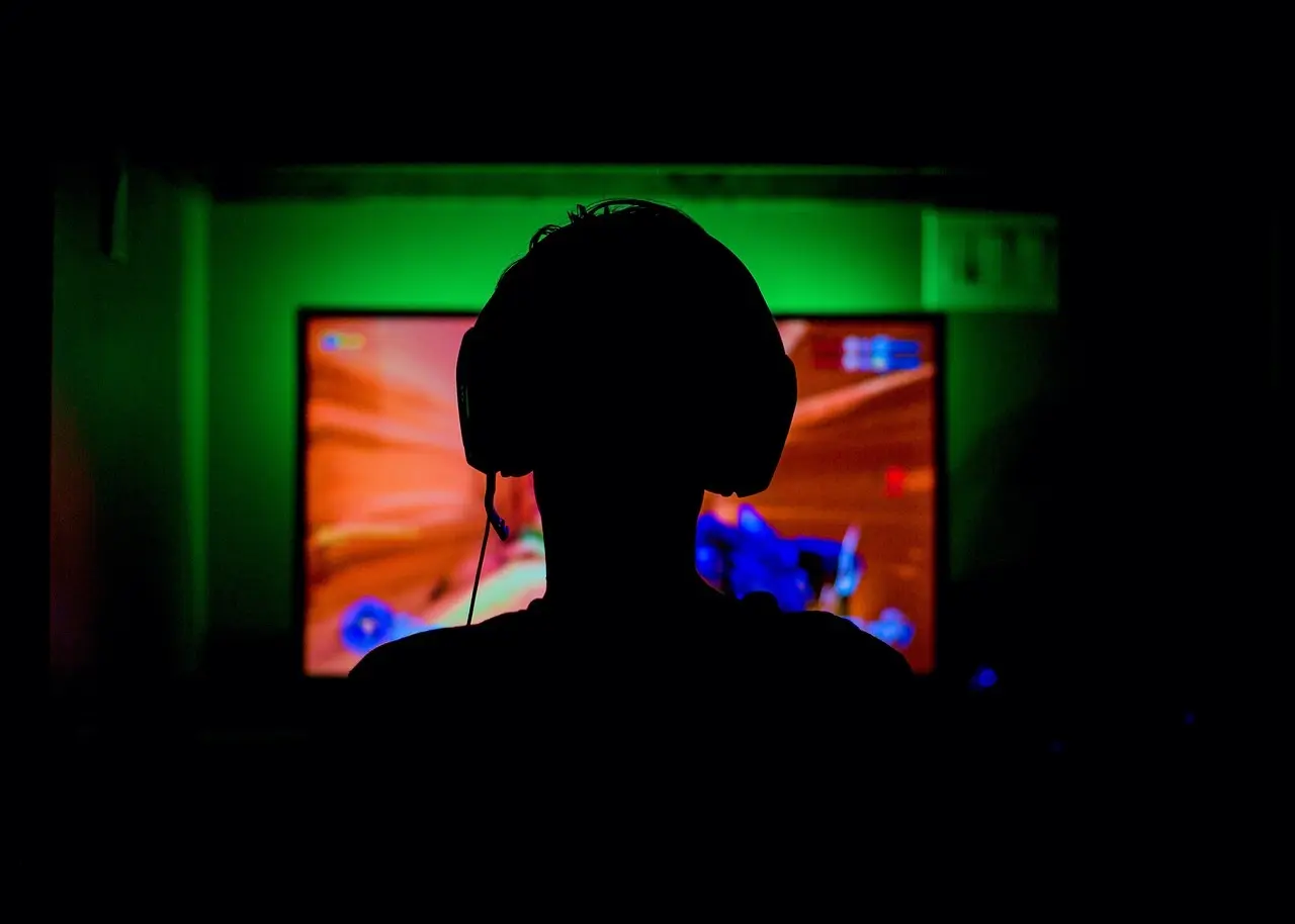 Silhuet af gamer foran farverig skærm