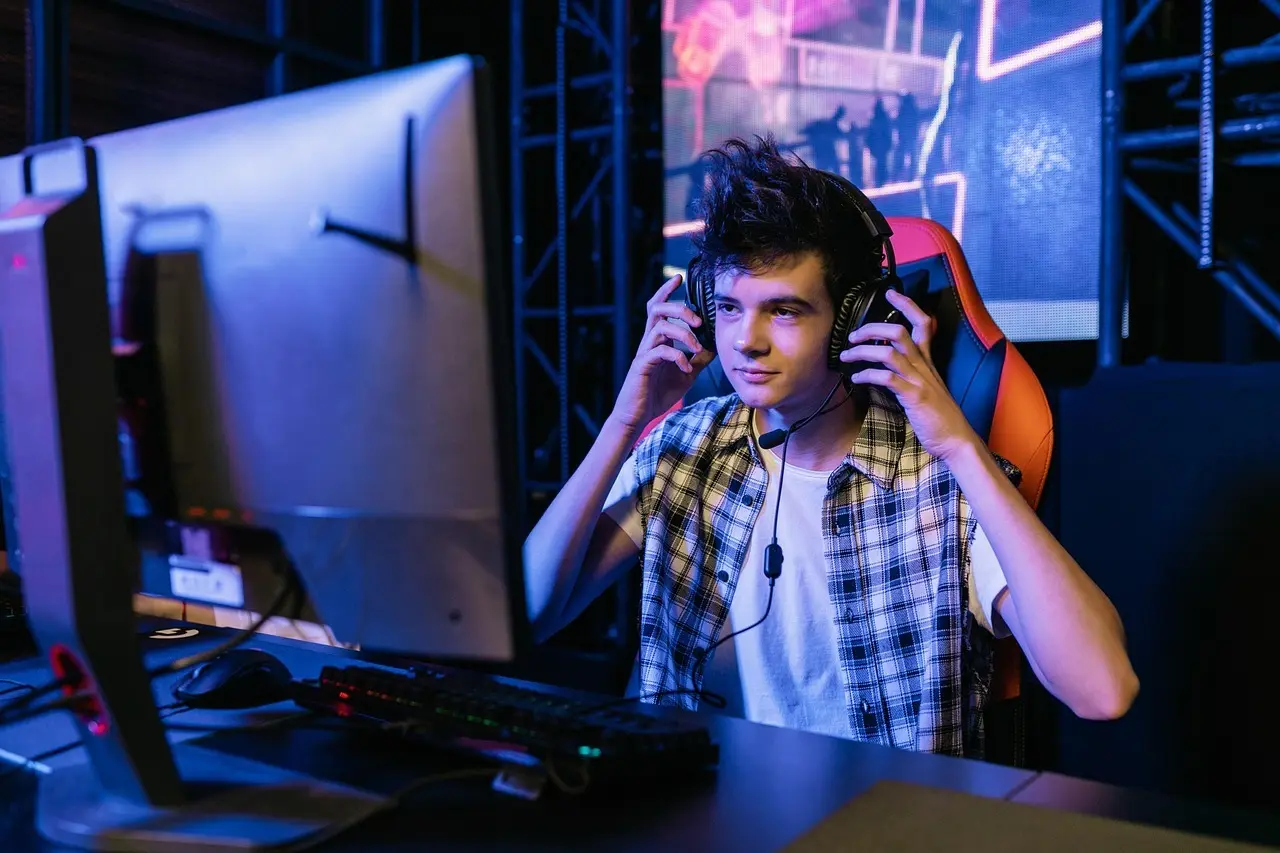 Ung gamer ved computer med headset